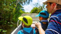 Two little kids boys and father making air boat tour in Florida wetland swamp at Everglades National Park in USA. Family, dad and children discovering wild nature and animals. Family having fun.