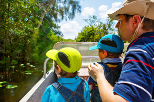 Two little kids boys and father making air boat tour in Florida wetland swamp at Everglades National Park in USA. Family, dad and children discovering wild nature and animals. Family having fun.